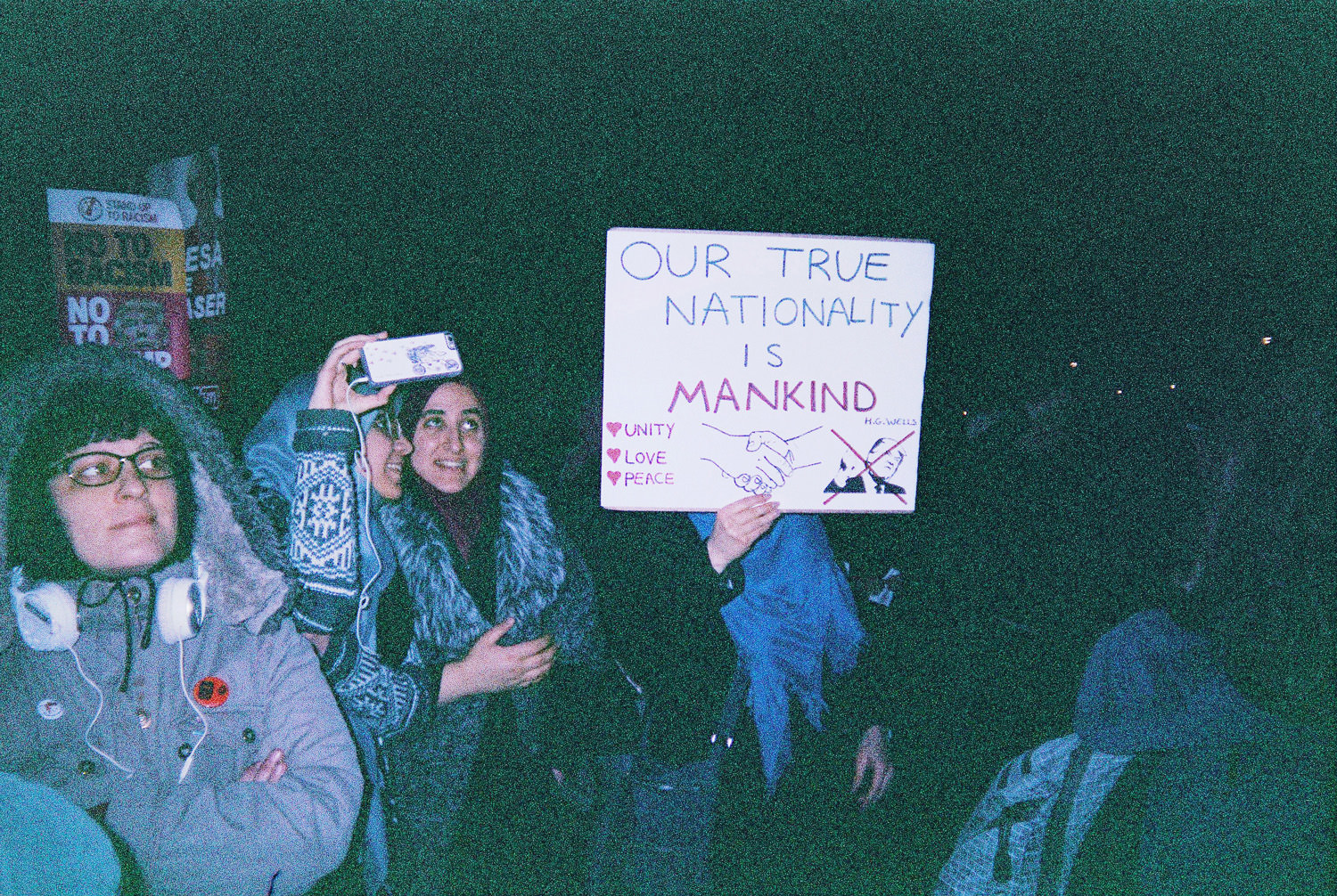 person holding sign reading "our true nationality is mankind" 