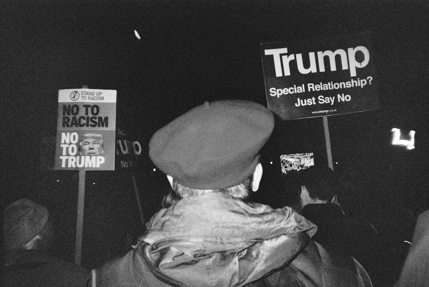 man in beret holding placard at rally against Trump state visit