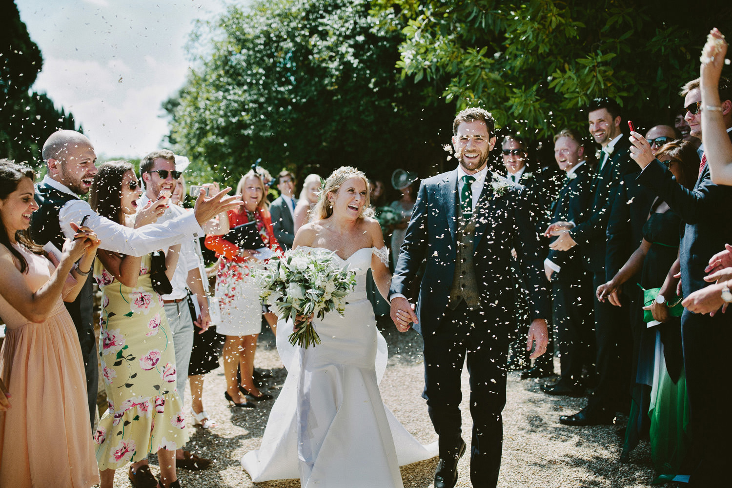 bride in a Hermione de Paula wedding dress and groom walk out of ceremony while confetti is thrown