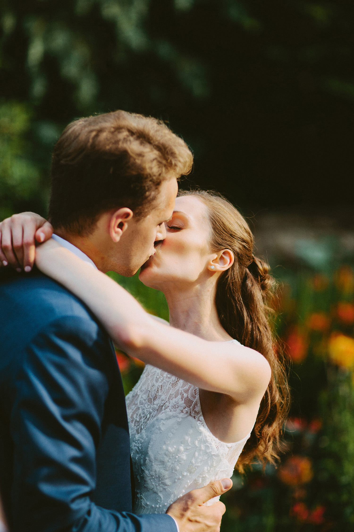 bride and groom kissing in sunlight in gardens of Rhodes House