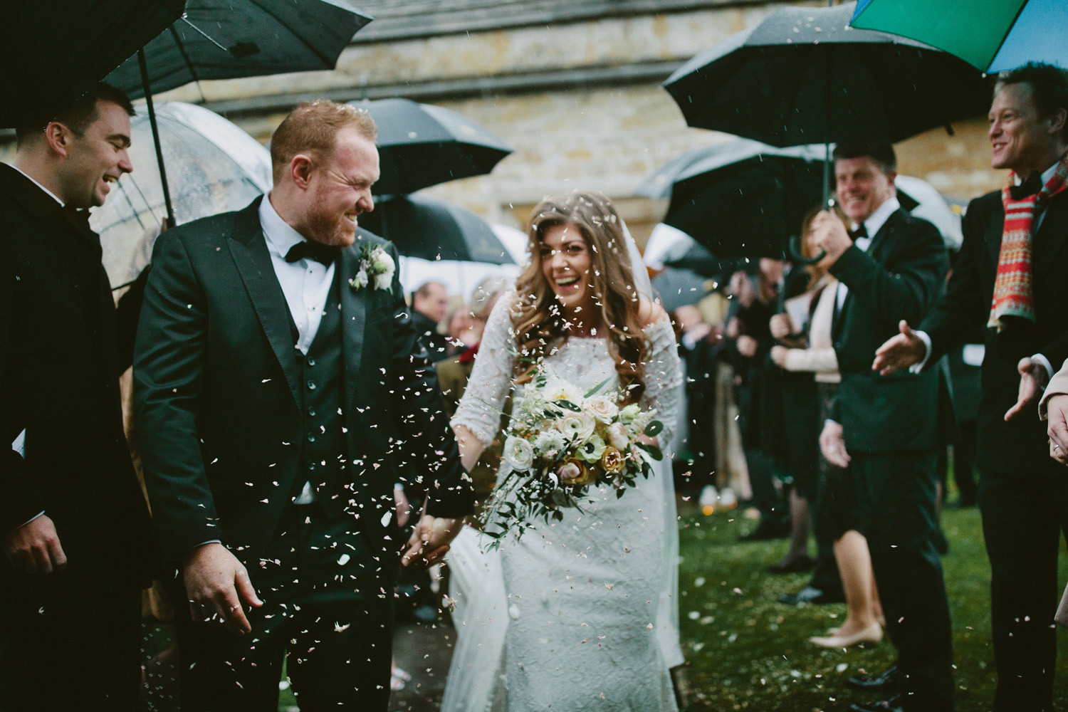 bride and groom smiling with confetti at church near Barnsley House