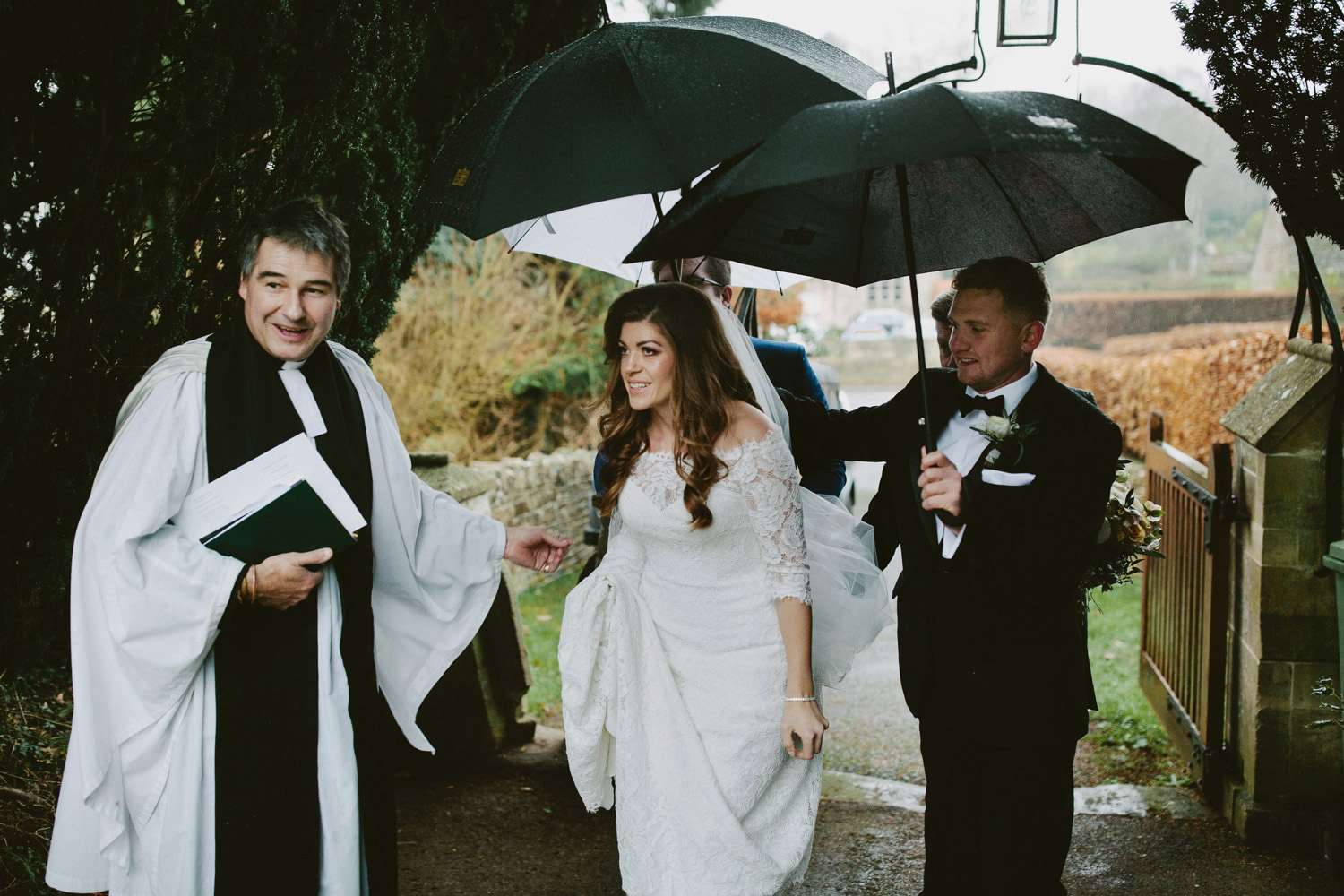 bride arriving at church with umbrellas