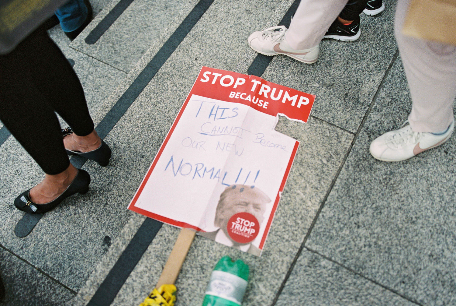 discarded placard on the floor reads "Stop Trump"