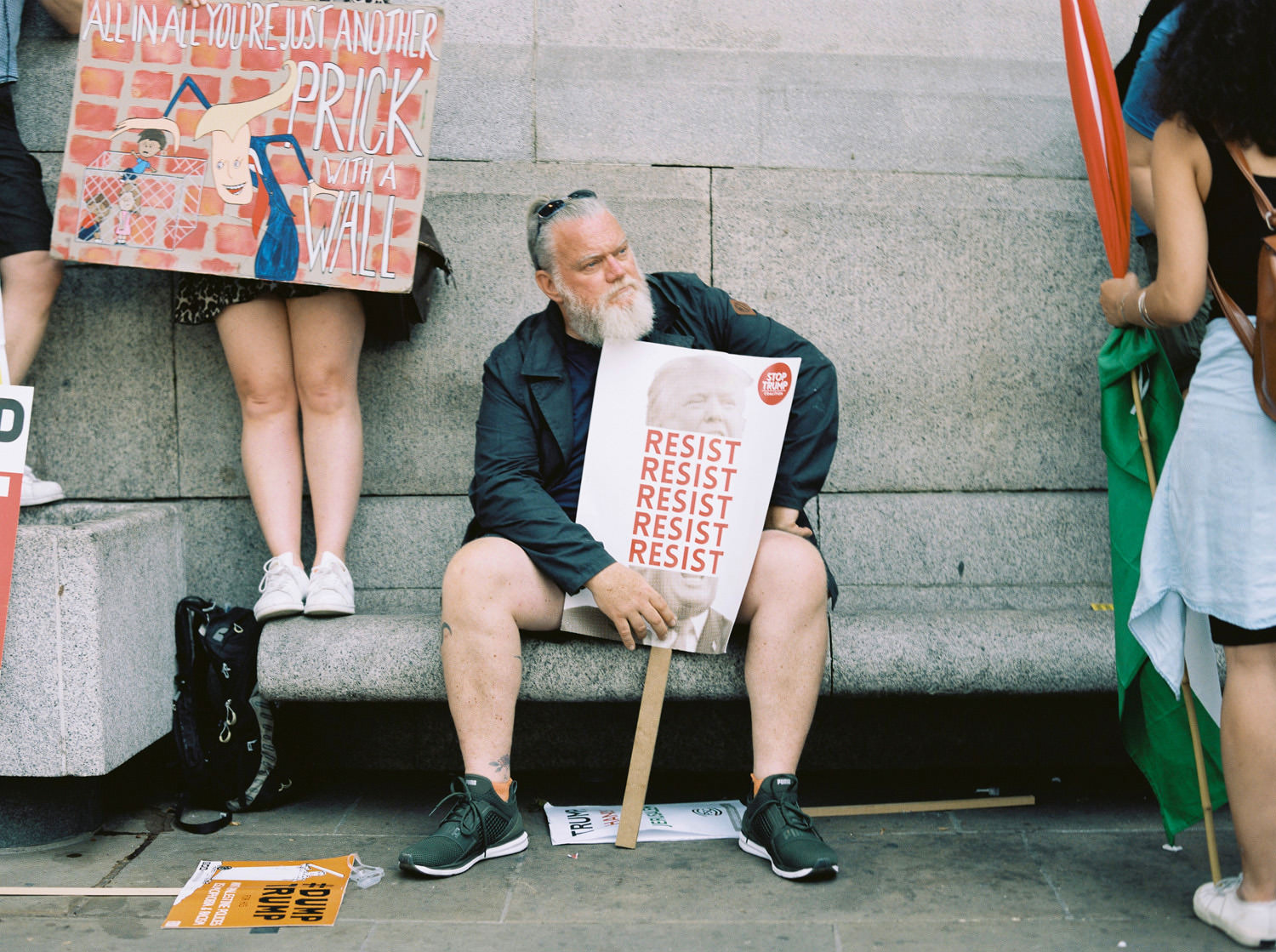 Man with beard at London Trump protest with sign that reads "resist, resist, resist"
