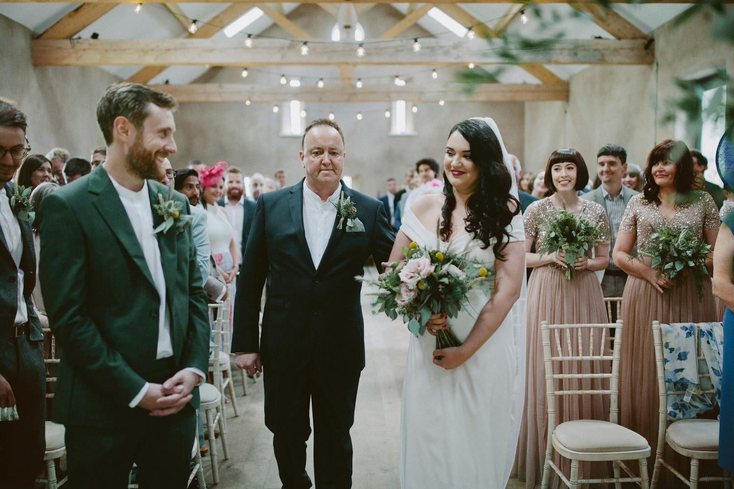 father walks with bride to front of ceremony while groom smiles