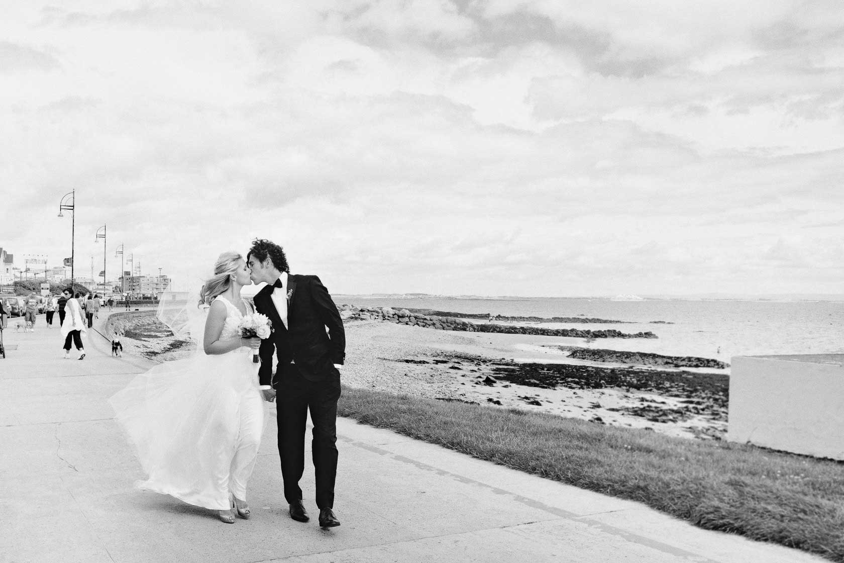 bride and groom kissing on seafront