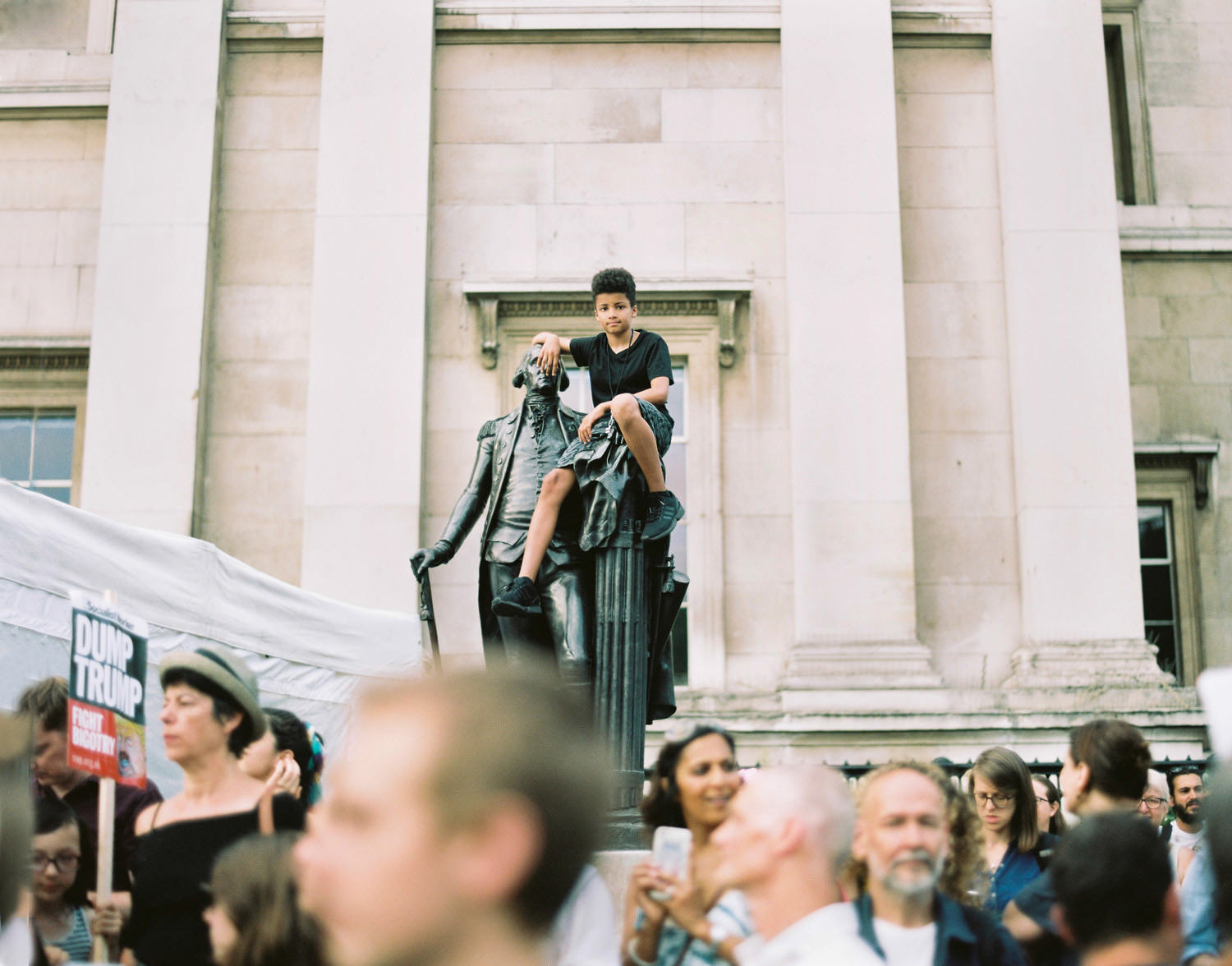 boy sat on statue at protest